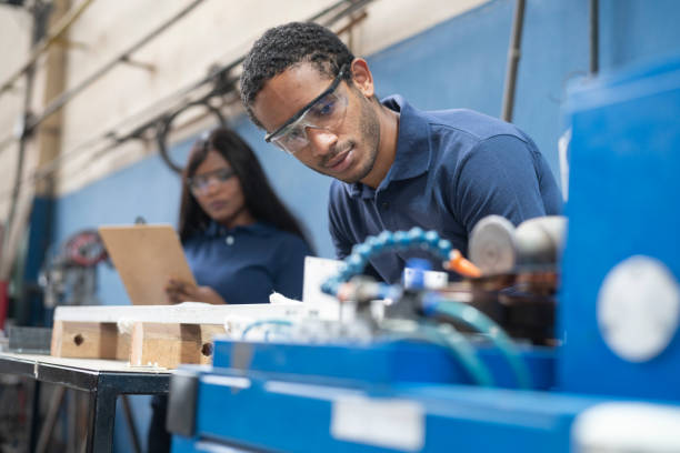 Multiracial workers operating machinery at solar panel factory