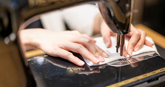 Female hand using vintage sewing machine scribbling fabric and repairing the cloth at home.