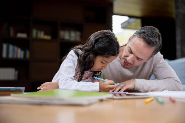 istock Father at home helping his daughter with her homework 1389796731