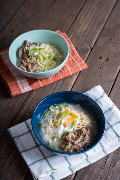 a blue bowl of gyudon ramen with egg and onion leeks