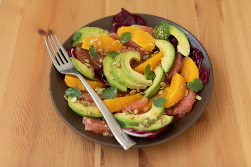 Citrus, avocado, and radicchio salad topped with pumpkin seeds and drizzled with an olive oil, lemon, garlic and dijon mustard vinaigrette dressing.