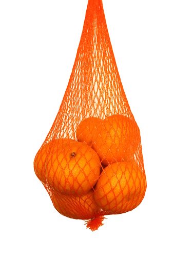 A bunch of tangerines in a mesh bag hang on a white background.
