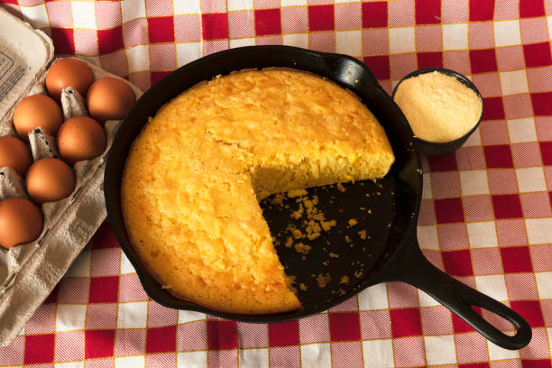 Cornbread in a Cast Iron Skillet with Eggs and Corn Flour on the Side Homemade cornbread in a cast iron skilet, with eggs and a container of corn flour arranged on the side. cornbread stock pictures, royalty-free photos & images