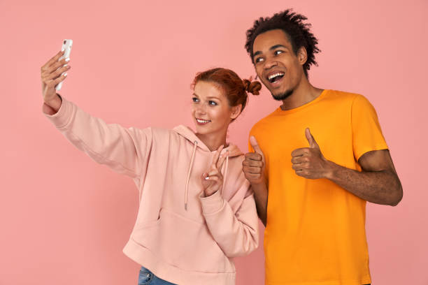 istock Cheerful black man laughs sincerely poses for selfie with ginger girlfriend makes peace sign gesture 1389806741