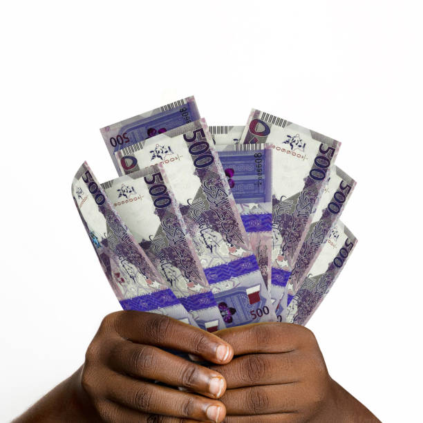 istock Black hands holding 3D rendered 500 Qatar riyal notes. closeup of Hands holding Qatari currency notes 1389809399