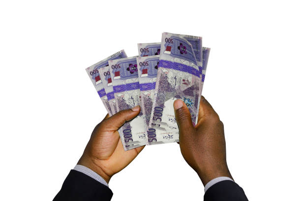 istock Black Hands in suit holding 3D rendered Qatar Riyal notes 1389809425