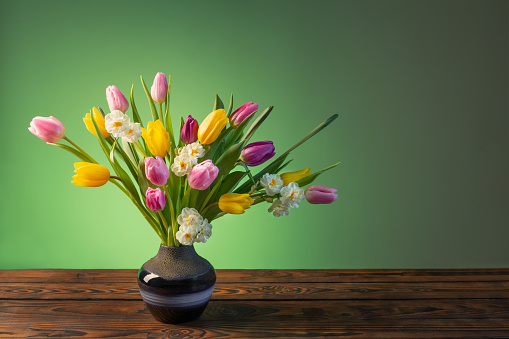 spring flowers in blue ceramic vase on wooden table