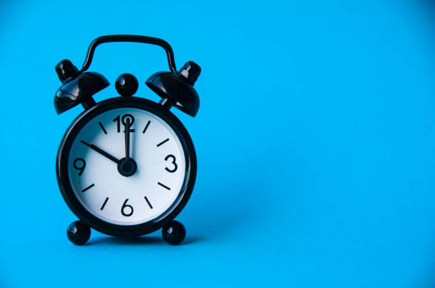 istock Black alarm clock isolated on blue background. The clock set at 10 o'clock. 1389815239