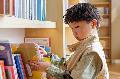 little boy looking for books on bookshelf