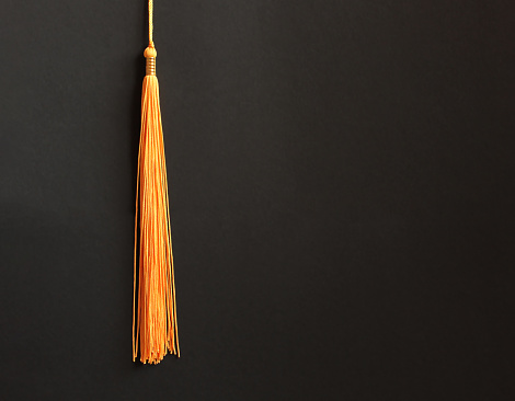 Graduation concept with academical tassel on balck background. Copy space
