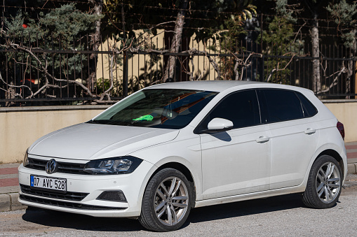 Side, Turkey – February 02 2022: silver Volkswagen Polo is parked  on the street on a warm summer day against the park