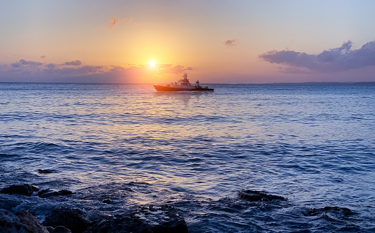 a warship at sea off the coast against the background of the setting sun