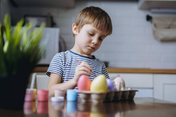 istock Cute little boy colouring eggs for easter 1389829278