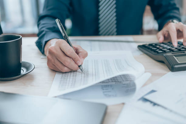 istock Accountant writing, checking and working on company data, document, report and calculator to calculate  on desk office. Accounting business concept. 1389830684