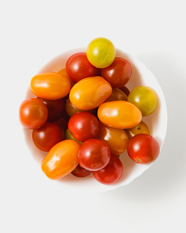 Various cherry tomatoes in bowl on white background. Fresh vegetables. Top view.