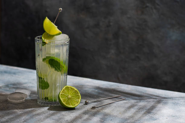 istock cold Mojito cocktail with rum, lime, ice cubes and mint. Tropical palm leaf shadow 1389831721