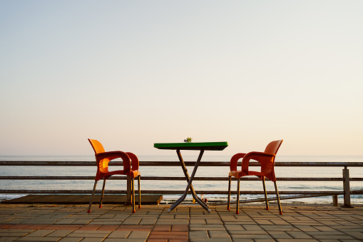 Orange plastic chairs with furniture at the seaside terrace with sky on background