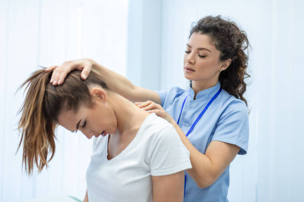 Licensed chiropractor or manual therapist doing neck stretch massage to relaxed female patient in clinic office. Young woman with whiplash or rheumatological problem getting professional doctor's help quiropráctico con licencia o terapeuta manual que realiza masajes de estiramiento del cuello a pacientes femeninas relajadas en el consultorio de la clínica. mujer joven con latigazo cervical o problema reumatológico que recibe ayuda de un médico profe