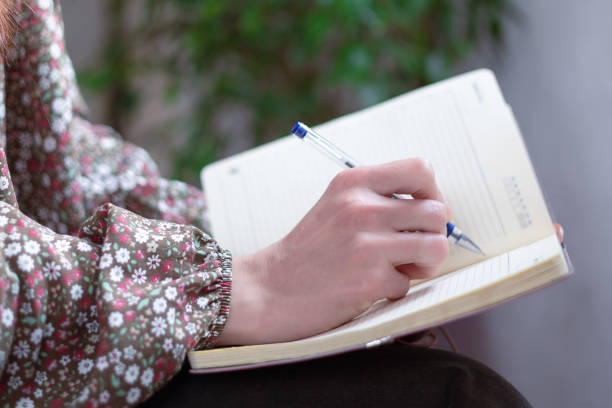 istock Close-up of a womans hands holding a notebook and a pen, and making a note. Journalism 1389836953