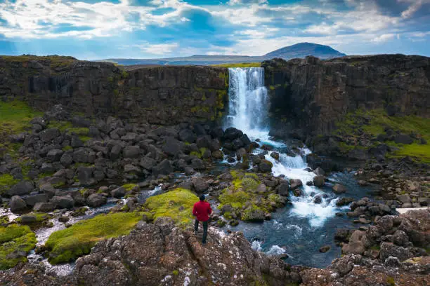 Photo of Tourist looking at the Oxarafoss waterfall in Iceland