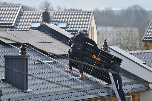 Vilnius, Lithuania - April 06, 2022: People installing solar panels on the roof in Vilnius, Lithuania.