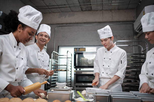 istock Chefs team in uniforms prepare to bake bread and pastry in stainless kitchen. 1389839548