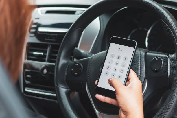 Hand holding cell phone with emergency number 911 in car stock photo