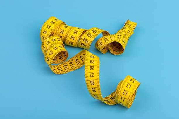 istock Yellow spiral tape measure on blue background. Centimeter. Space for text. 1389841073