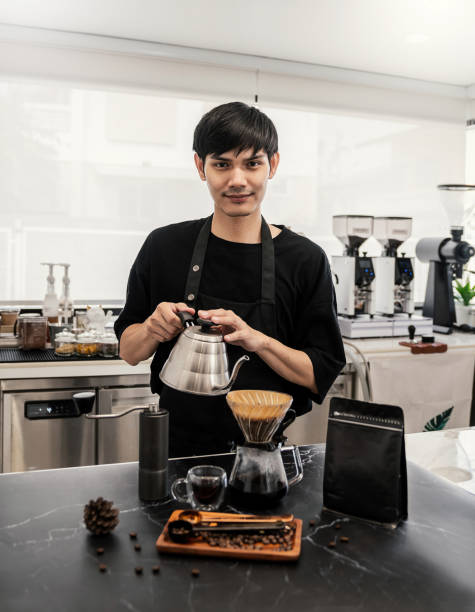 スタートアップで成功した中小企業のオーナーは、カフェのろ紙コーヒースローバーにお湯を滴り落ちるハンサムなアジア人男性をスメします。ポートレート若い男バリスタカフェオーナー� - コーヒー　淹れる ストックフォトと画像