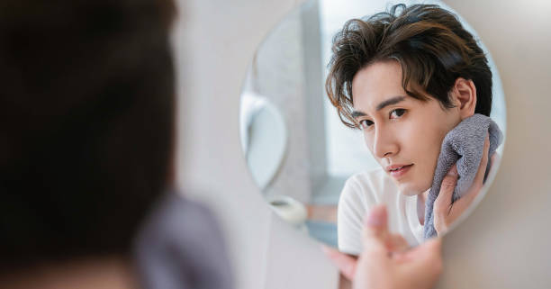 retrato en primer plano de un hermoso chico asiático con rutina de maquillaje de espejo con espacio de copia. influencer de belleza chico con piel de brillo perfecto vestido. cuidado de la salud hombre estilo de vida estilo de vida concepto de blogger cos - korean culture fotos fotografías e imágenes de stock