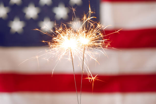 Bright burning sparklers against American flag, closeup Bright burning sparklers against American flag, closeup fourth of july stock pictures, royalty-free photos & images