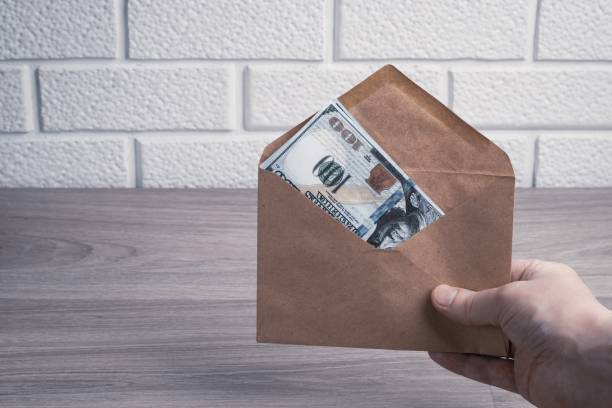istock The hand holds a paper envelope with dollar bills. 1389846635