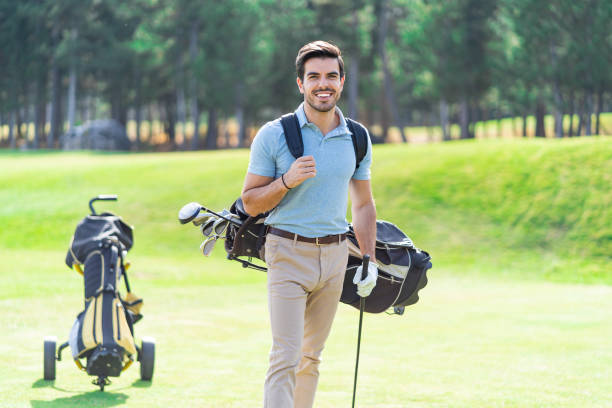 istock Smiling golf player standing on a golf course with a    backpack on his back and holding a golf club in his hand 1389850040