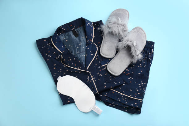zapatillas de casa, máscara para dormir y pijama sobre fondo azul claro, tendido plano - ropa de dormir fotografías e imágenes de stock