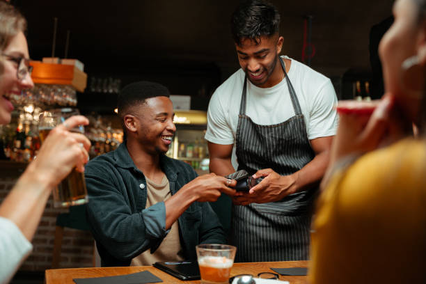 diverse friends out for dinner paying with cellular device