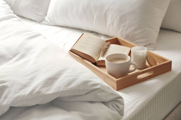 Cup of aromatic coffee, book and candle on bed with soft blanket indoors Cup of aromatic coffee, book and candle on bed with soft blanket indoors duvet stock pictures, royalty-free photos & images