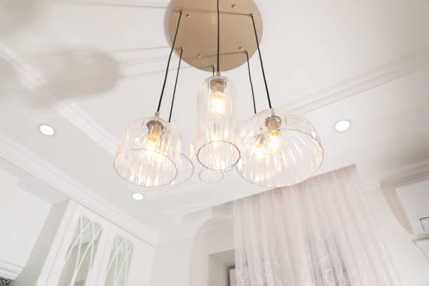 istock Stylish pendant lamp with light bulbs on ceiling in  modern room 1389852680
