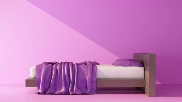 beam of light falls on a stylish bed on a purple background stock photo