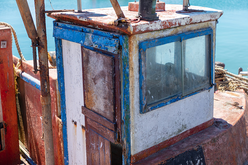 Selective focus on the door, window and cabin of an old disused fishing trawler.