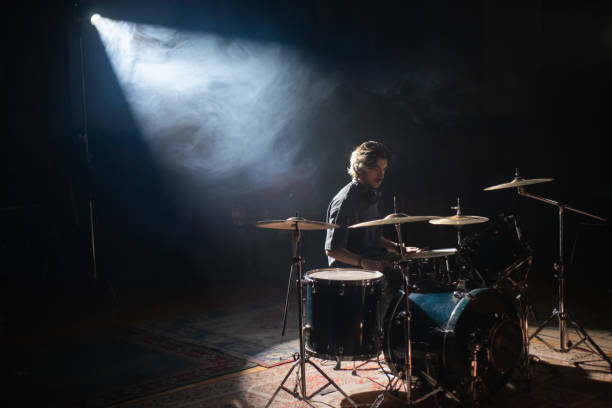 istock Young drummer sitting in spotlight and training in hall 1389854126