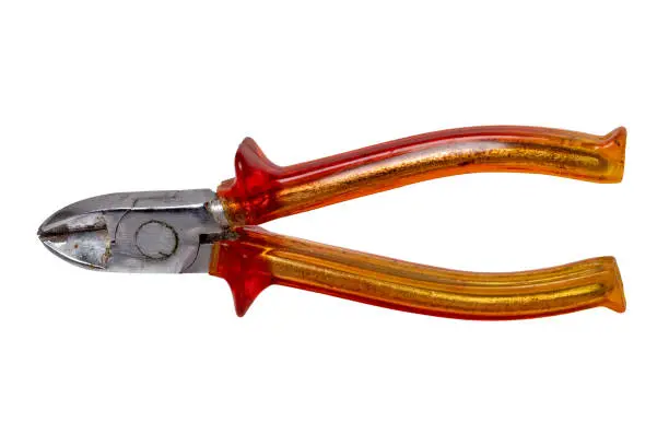 Closeup of an old rusty pair of cutting pliers or side cutters for cutting wire with red plastic handles isolated on white background. Clipping path. Electrician's tool.