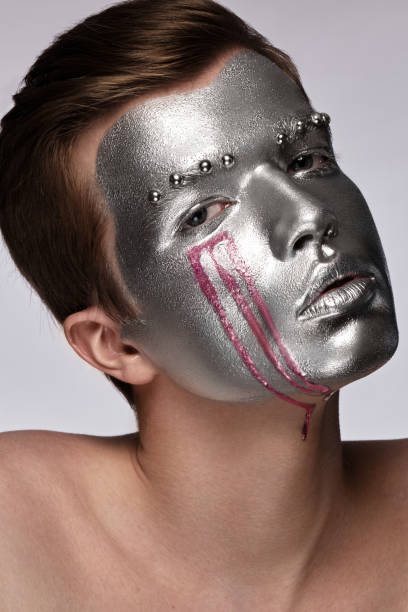 istock Young man with art creative art make-up with silver paint on his face. 1389855669