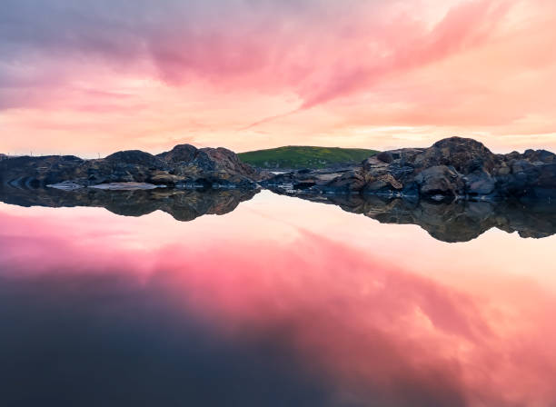 luce del sole nel tardo pomeriggio e riflessione sullo scenario roccioso costiero. - reflection water rock beach foto e immagini stock