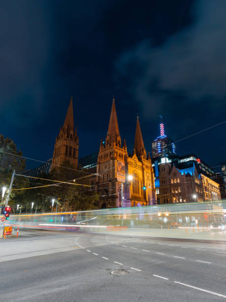 Melbourne, Australia - April 1, 2022: Tram passing through St Paul's Cathedral at night.