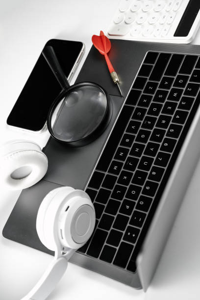 istock Computer on white background board, magnifying glass, darts, headphones and calculator 1389859666
