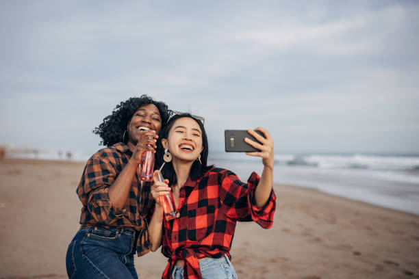 istock Two friends walking the beach drinking soda and taking a selfie 1389859958
