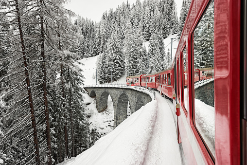 Train ride in idyllic winter landscape in Switzerland. The Rhaetian Railway is a railroad transport company. The route network is mainly located in the canton of Graubünden.