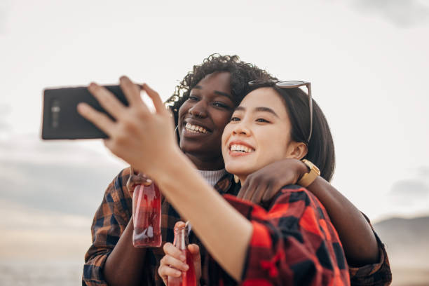 istock Two friends walking the beach drinking soda and taking a selfie 1389860760