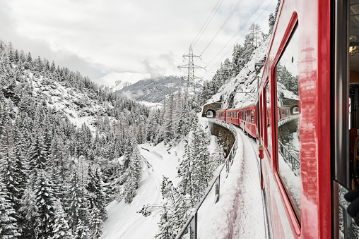 Train ride in idyllic winter landscape in Switzerland. The Rhaetian Railway is a railroad transport company. The route network is mainly located in the canton of Graubünden.