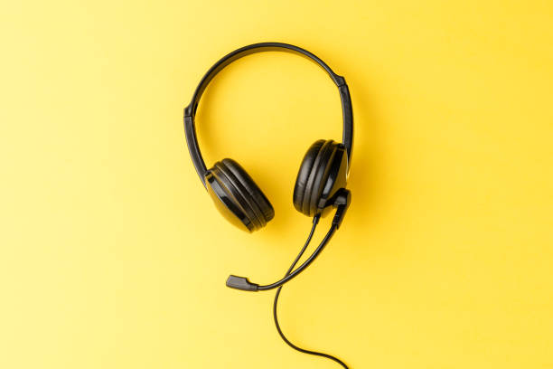 istock Call center concept with helpdesk headphones on yellow background with copyspace 1389861006